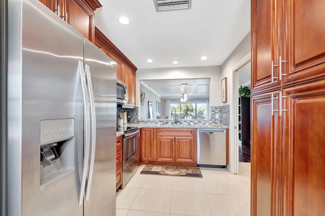 kitchen featuring decorative backsplash, sink, light stone countertops, and appliances with stainless steel finishes