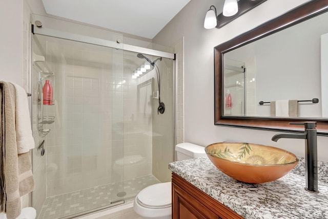 bathroom with vanity, toilet, and a shower with door