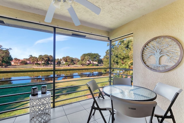 sunroom / solarium featuring a water view and ceiling fan