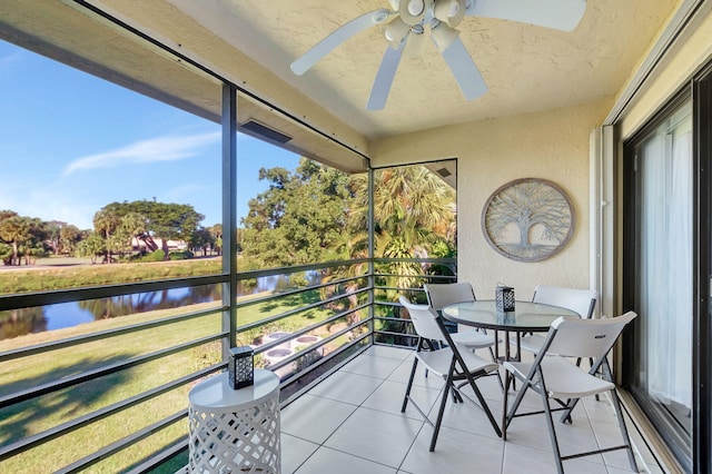 sunroom / solarium featuring ceiling fan, a water view, and a healthy amount of sunlight