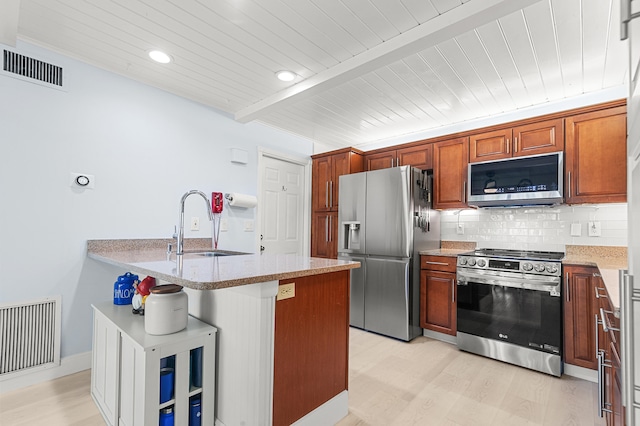 kitchen with beam ceiling, sink, stainless steel appliances, a kitchen bar, and light wood-type flooring