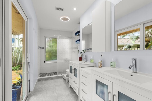 bathroom with tiled shower, vanity, toilet, and a bidet