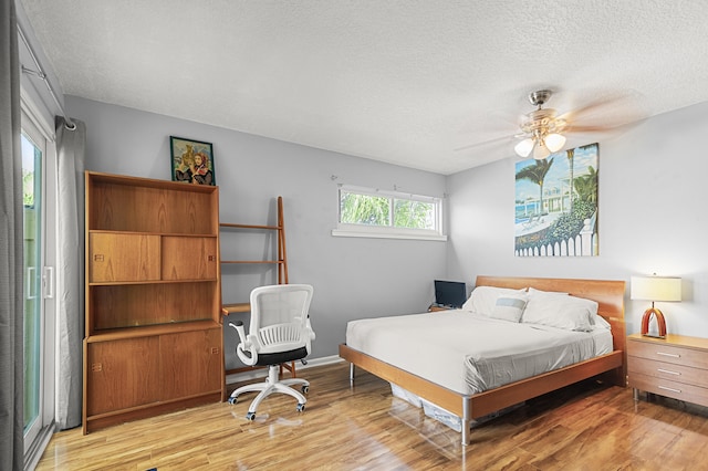 bedroom with ceiling fan, light hardwood / wood-style floors, and a textured ceiling