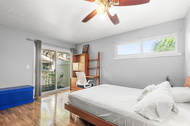 bedroom with hardwood / wood-style floors, access to outside, multiple windows, and ceiling fan