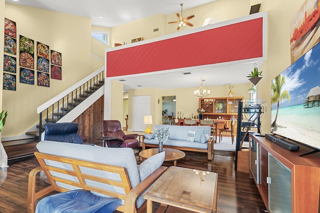 living room featuring ceiling fan with notable chandelier, dark hardwood / wood-style floors, and a high ceiling