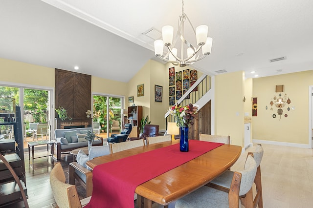 dining room with a notable chandelier, a textured ceiling, lofted ceiling, a fireplace, and light wood-type flooring