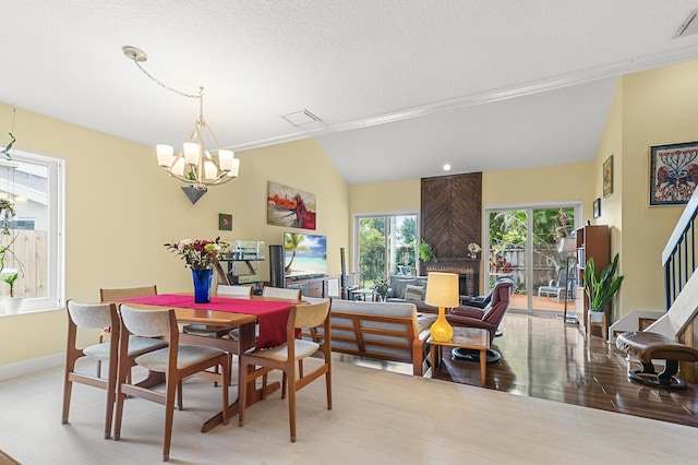 dining space with vaulted ceiling, a textured ceiling, an inviting chandelier, and light hardwood / wood-style flooring