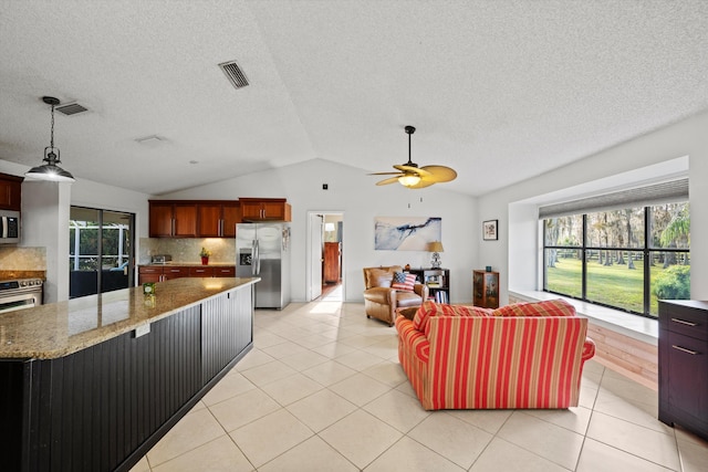 kitchen featuring vaulted ceiling, decorative backsplash, ceiling fan, appliances with stainless steel finishes, and light stone counters