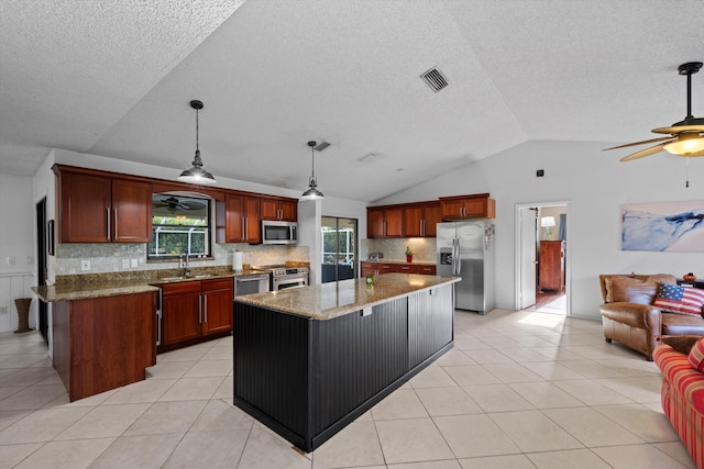 kitchen with decorative backsplash, appliances with stainless steel finishes, a kitchen island, hanging light fixtures, and lofted ceiling