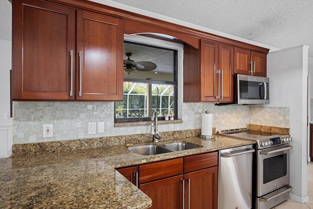 kitchen with appliances with stainless steel finishes, backsplash, light stone counters, a textured ceiling, and sink