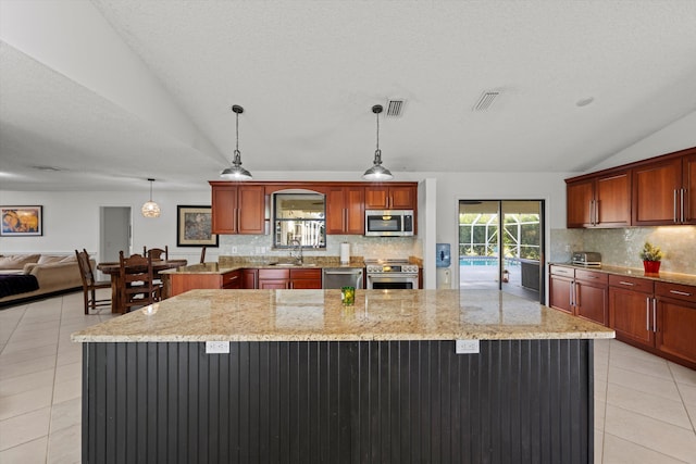 kitchen featuring appliances with stainless steel finishes, a textured ceiling, vaulted ceiling, pendant lighting, and a kitchen island