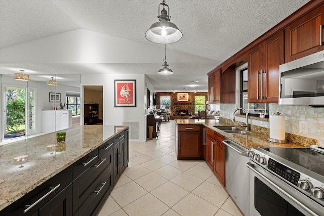 kitchen featuring hanging light fixtures, sink, vaulted ceiling, a fireplace, and appliances with stainless steel finishes