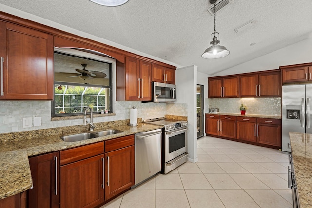 kitchen with sink, stainless steel appliances, pendant lighting, vaulted ceiling, and light tile patterned flooring