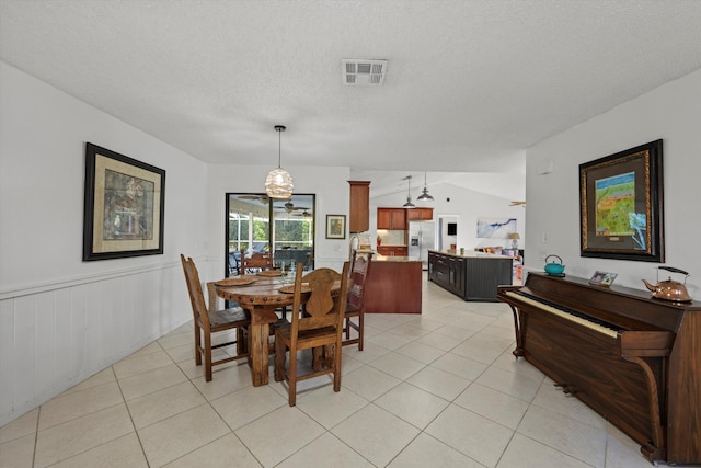 dining room with a textured ceiling, light tile patterned floors, and vaulted ceiling