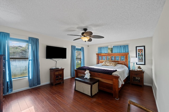 bedroom with ceiling fan, dark wood-type flooring, and a textured ceiling