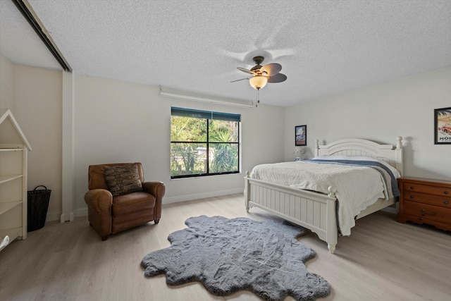 bedroom with a textured ceiling, light hardwood / wood-style flooring, and ceiling fan