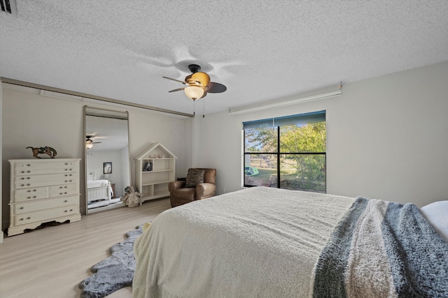 bedroom featuring ceiling fan, light hardwood / wood-style flooring, and a textured ceiling