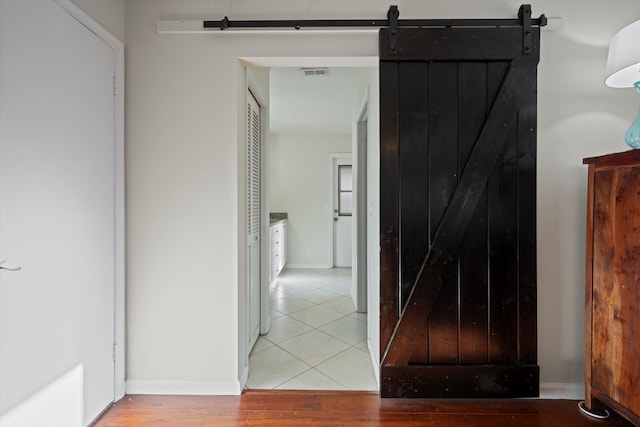 hall with a barn door and wood-type flooring