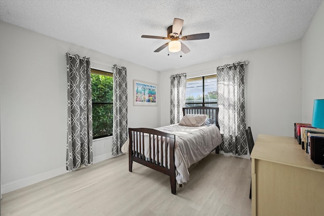 bedroom with ceiling fan, light wood-type flooring, and a textured ceiling