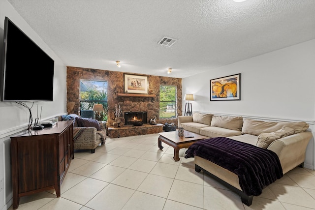 tiled living room with a textured ceiling and a stone fireplace