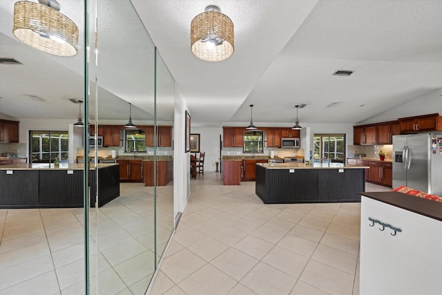 kitchen featuring appliances with stainless steel finishes, a center island, decorative light fixtures, and tasteful backsplash