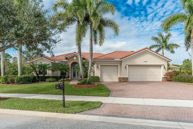 mediterranean / spanish home featuring a garage and a front lawn