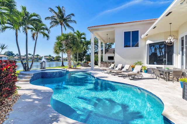 view of pool featuring an in ground hot tub, a water view, and a patio