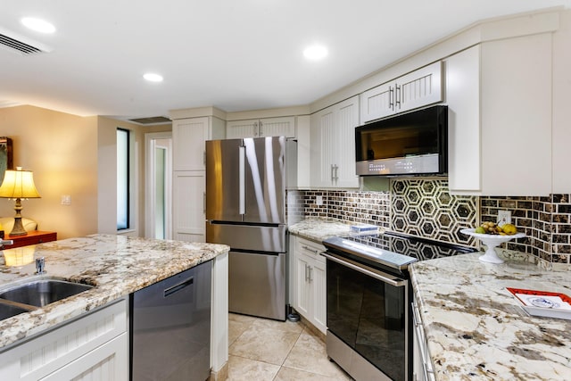 kitchen featuring sink, light stone countertops, appliances with stainless steel finishes, tasteful backsplash, and light tile patterned flooring