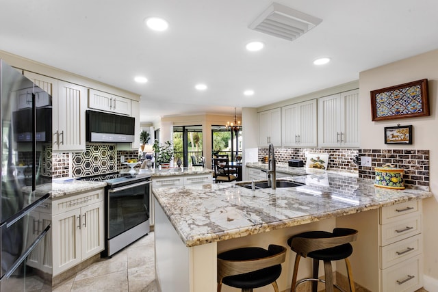 kitchen featuring sink, light stone counters, appliances with stainless steel finishes, a kitchen bar, and kitchen peninsula