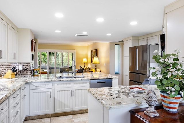 kitchen featuring kitchen peninsula, light stone countertops, stainless steel appliances, sink, and white cabinets