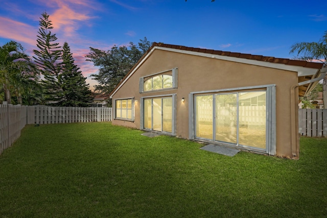 back house at dusk featuring a yard