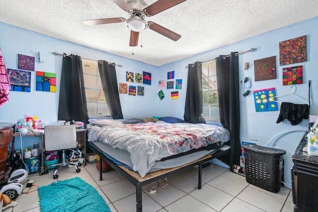 bedroom with ceiling fan, light tile patterned floors, and a textured ceiling