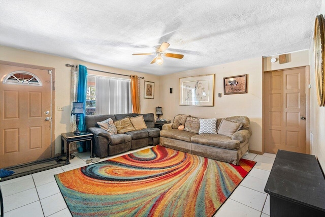 living room featuring ceiling fan, light tile patterned floors, and a textured ceiling