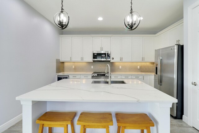 kitchen featuring light stone countertops, dishwasher, sink, an island with sink, and white cabinets