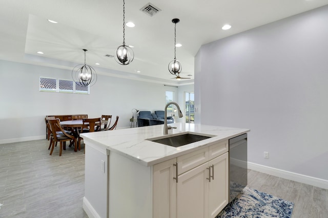 kitchen with light stone counters, decorative light fixtures, visible vents, stainless steel dishwasher, and a sink