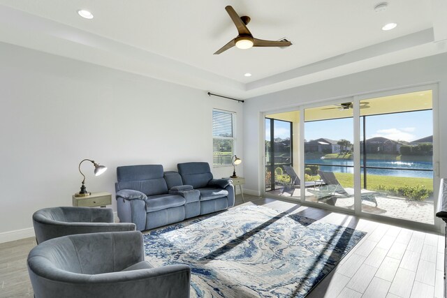 living room with a raised ceiling and ceiling fan