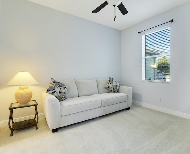 living room with light carpet, baseboards, and a ceiling fan