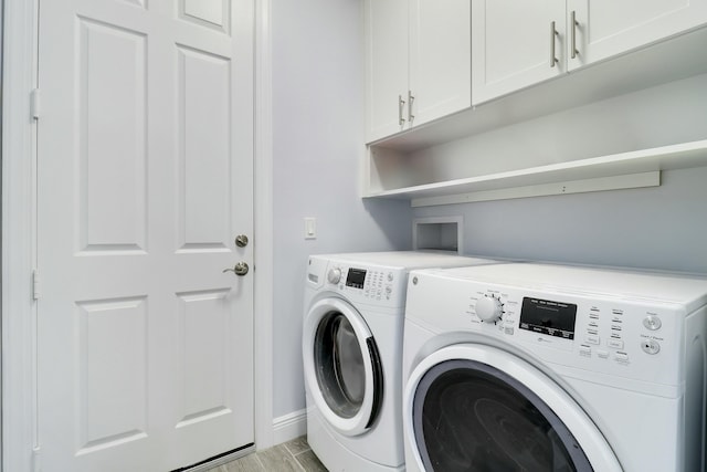 laundry area featuring washer and dryer, baseboards, cabinet space, and light wood finished floors