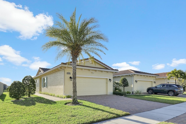 view of front facade featuring a garage, decorative driveway, a front yard, and stucco siding