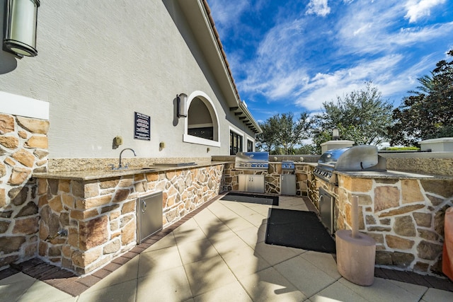 view of patio featuring an outdoor kitchen, grilling area, and a sink