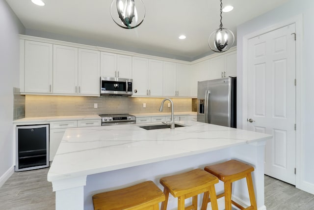 kitchen featuring stainless steel appliances, a sink, white cabinets, and decorative backsplash