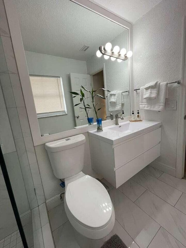 bathroom featuring vanity, a textured ceiling, and toilet