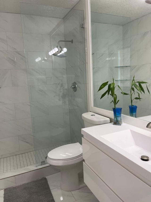 bathroom featuring toilet, vanity, and tiled shower