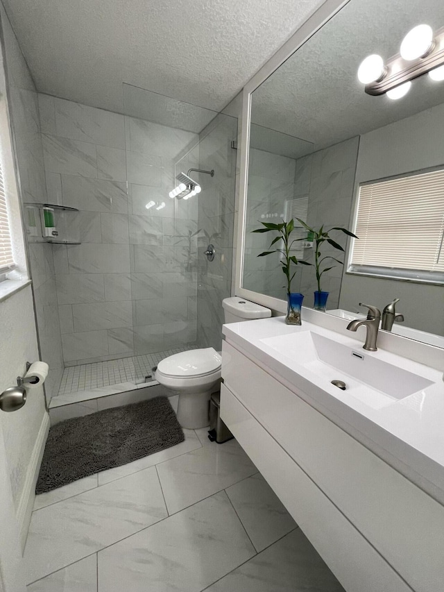 bathroom with tiled shower, a textured ceiling, vanity, and toilet