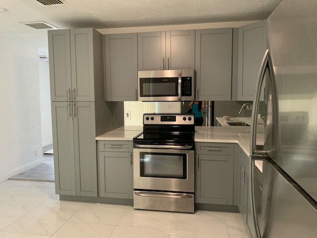 kitchen featuring gray cabinets, sink, and stainless steel appliances