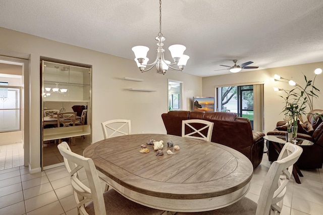 dining space featuring ceiling fan with notable chandelier, light tile patterned floors, and a textured ceiling