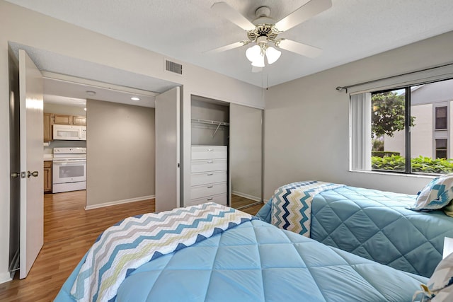 bedroom featuring ceiling fan, a closet, a textured ceiling, and light hardwood / wood-style flooring