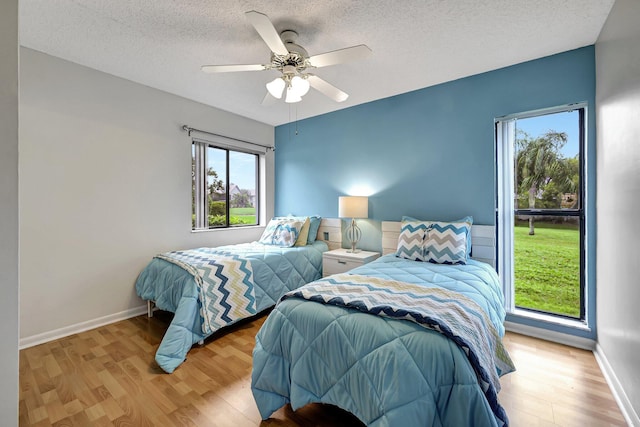 bedroom with ceiling fan, a textured ceiling, and light hardwood / wood-style flooring