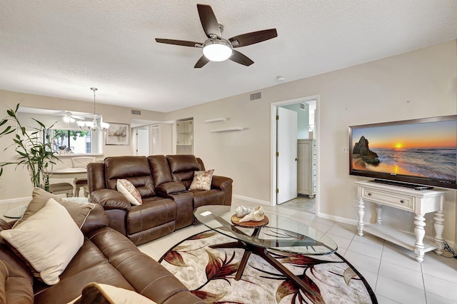 living room with ceiling fan with notable chandelier, light tile patterned floors, and a textured ceiling