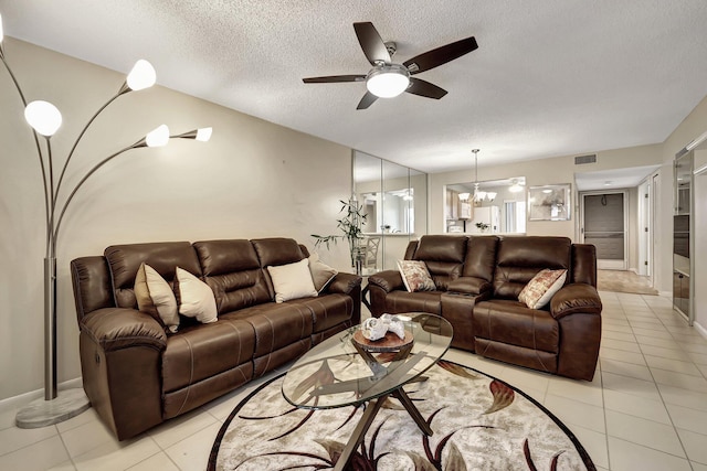 tiled living room featuring ceiling fan with notable chandelier and a textured ceiling